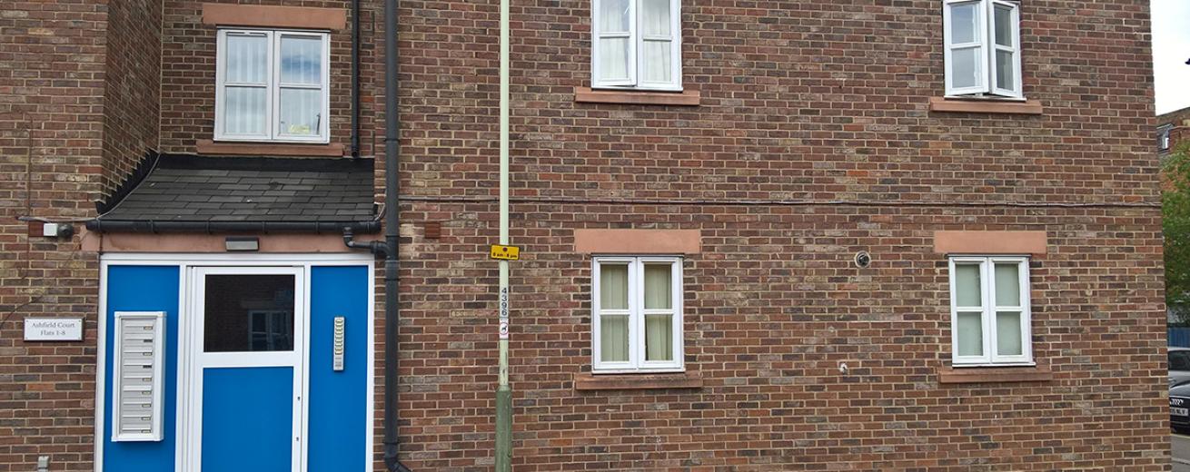 Two storey brick property at Ashfield Court, with vibrant blue and white secure door access.