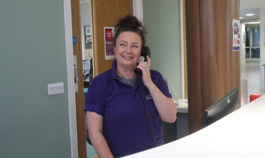 Sanctuary Supported Living Staff member on the phone wearing a purple uniform polo top