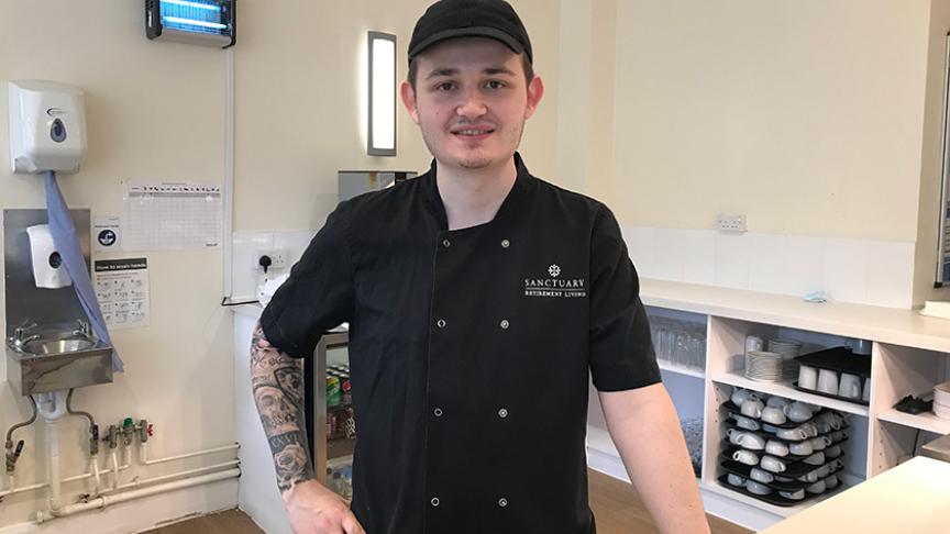 A Chef Manager standing in the kitchen of a Sanctuary Supported Living scheme, dressed in black chefs overalls