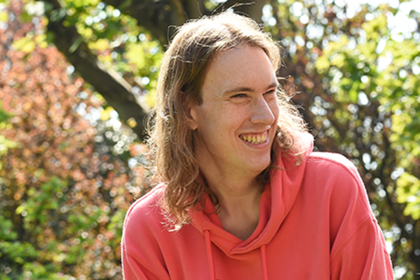 SSL resident smiling, photographed outside by a tree