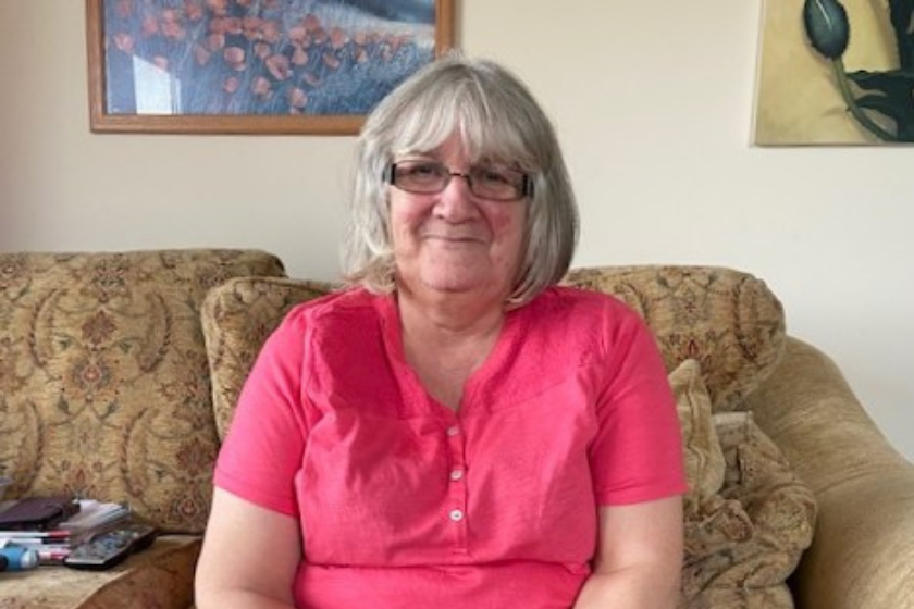 A woman sits and smiles in an armchair