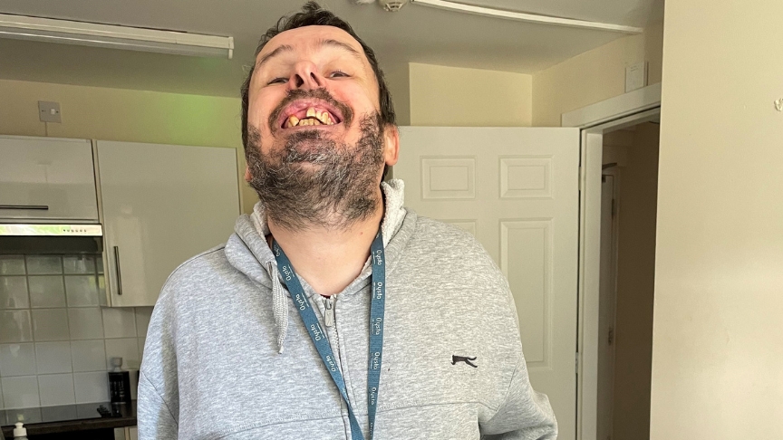 Sanctuary resident smiling at the camera, wearing an Oysta device around his neck