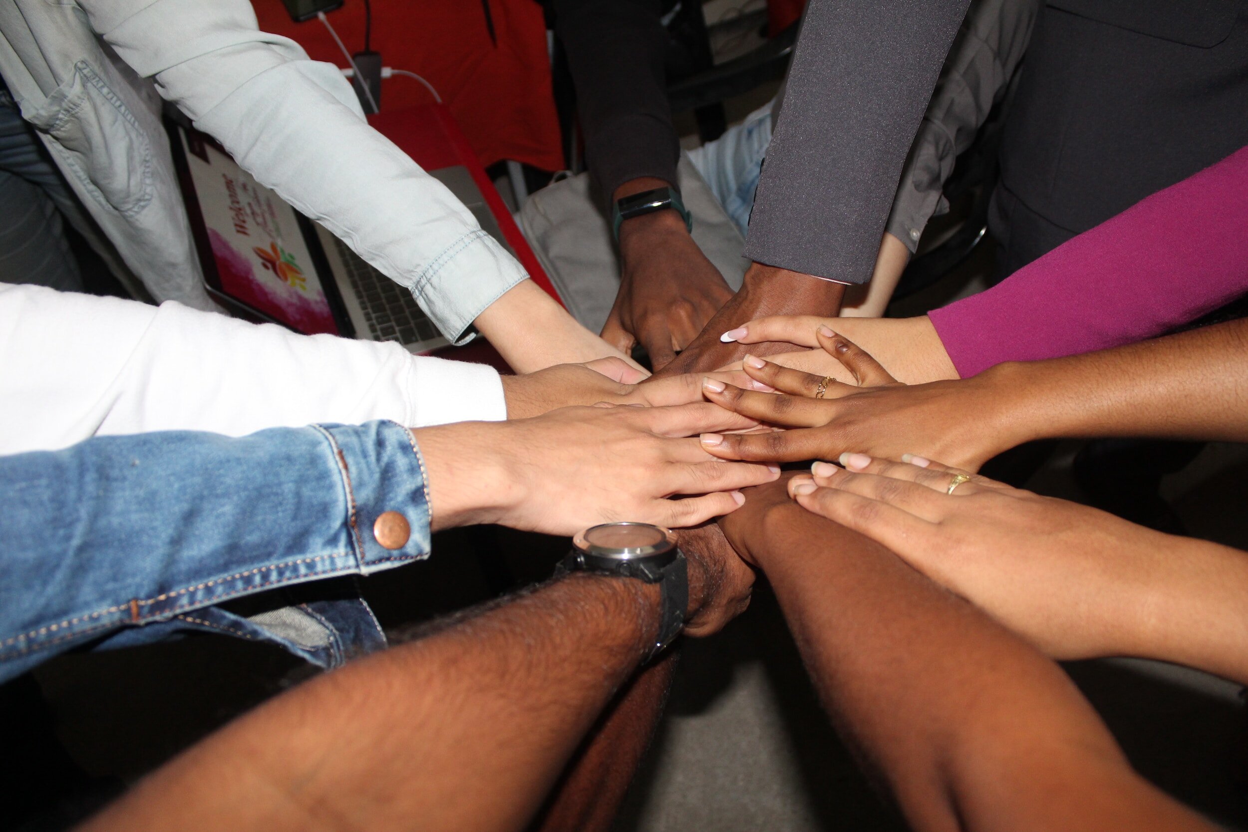 An image of 9 people's hands altogether in a circle