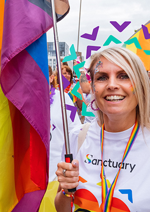 Sanctuary staff and residents wearing white shirts with rainbow hearts on carrying rainbow flags taking part in a march for a PRIDE event