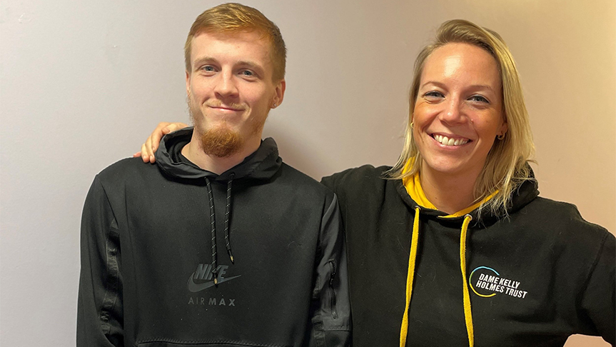 Supported housing resident with his Dame Kelly Homes Trust athlete mentor A young man and a woman stood smiling at the camera. She is wearing a Dame Kelly Holmes Trust hoody.