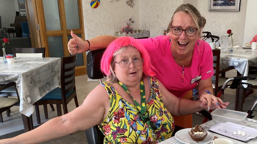 A SSL resident wearing a pink wig and a member of staff smiling and celebrating PRIDE