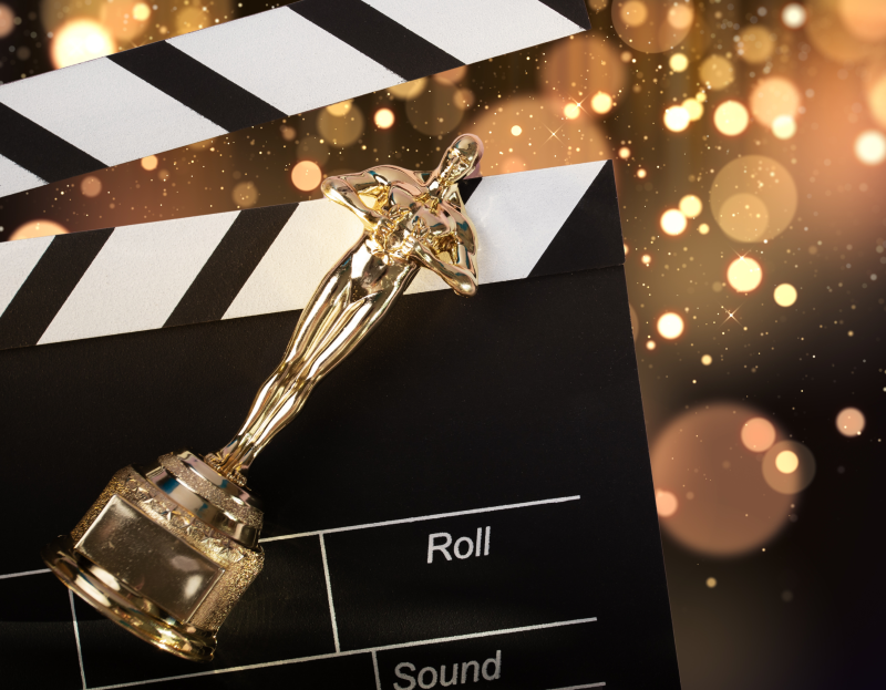 A gold Oscar award lay across a cinematic clapperboard.
