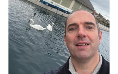 Project Worker Stuart Buchan posing with two swans swimming