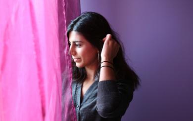 Stock image of a woman looking through a curtain