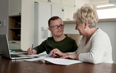 A stock image of two people sat in front of a laptop, planning something
