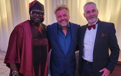 Samson, host Martin Roberts and Dave Shaw stood smiling wearing smart clothes celebrating their success
