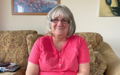 A woman called Mary Lord sits and smiles in an armchair