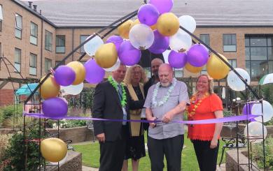 Craig Moule and members of staff at Baskeyfield House in the new memorial garden at Baskeyfield house stood under some purple balloons with one of them cutting a purple ribbon