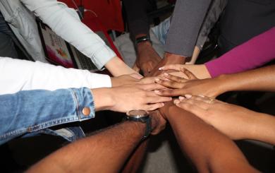 An image of 9 people's hands altogether in a circle