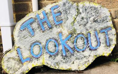 A log sign reads "The Lookout" in blue paint