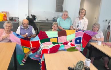 Residents at Jazz Court proudly displaying the kitted blanket they have made for a charity raffle