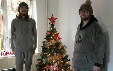 Two residents at Sudbury Young People Supported Housing wearing winter hats in front of a decorated Christmas tree