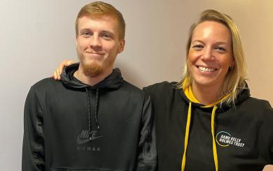 A young man and a woman stood smiling at the camera. She s wearing a Dame Kelly Holmes Trust hoody.