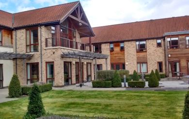 Exterior of Exning Court a two storey purpose built retirement community with large windows and a first floor balcony