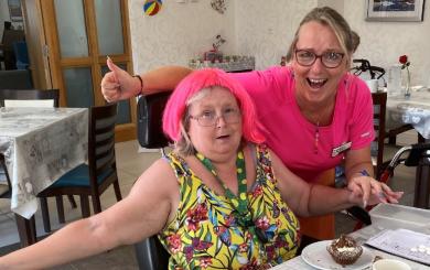 A SSL resident wearing a pink wig and a member of staff smiling and celebrating PRIDE