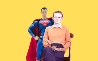 An image of Neil, a man sat wearing a yellow jumper in front of a Superman statue.