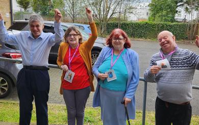 Two men and two women, all residents at Sarnes Court learning disability service, stood outside the service entrance and cheering and smiling for the camera.
