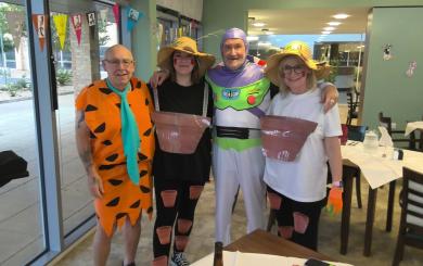Two women and two older men all dressed up, stood together and smiling at the camera. One man is Fred Flintstone, the other is Buzz Lightyear and the two women are Bill and Ben the Flowerpot Men.