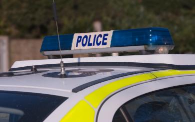 Close up of the top of a police car with white and neon yellow body work and blue lights on top