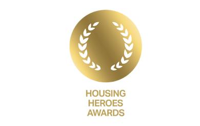 Gold circular emblem with laurel leaves and text below reading 'HOUSING HEROES AWARDS'