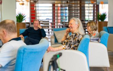 4 residents are seated in a communal area laughing and smiling