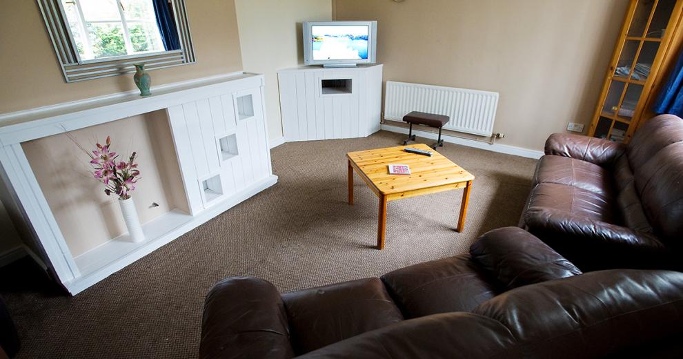 Comfortable and minimal living area, comprising of two leather sofas, tv unit and feature wall fireplace.