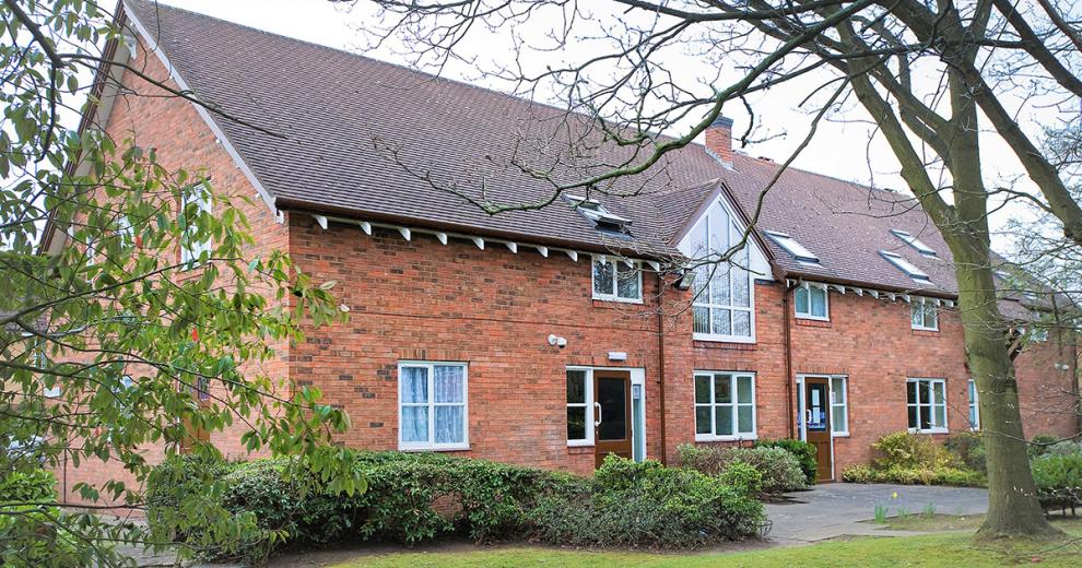 Classic red brick building with prominent windows facing a grassy area.