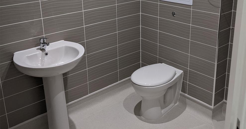 Crisp and clean grey tiled bathroom with white grout and coordinating bathroom suite.