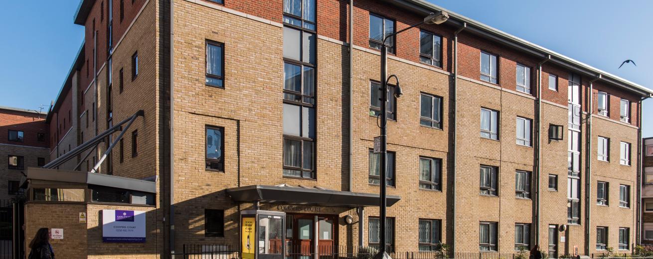 A four storey new-build brick apartment block, located by a main road with gated access to the entrance and a secure gated carpark.