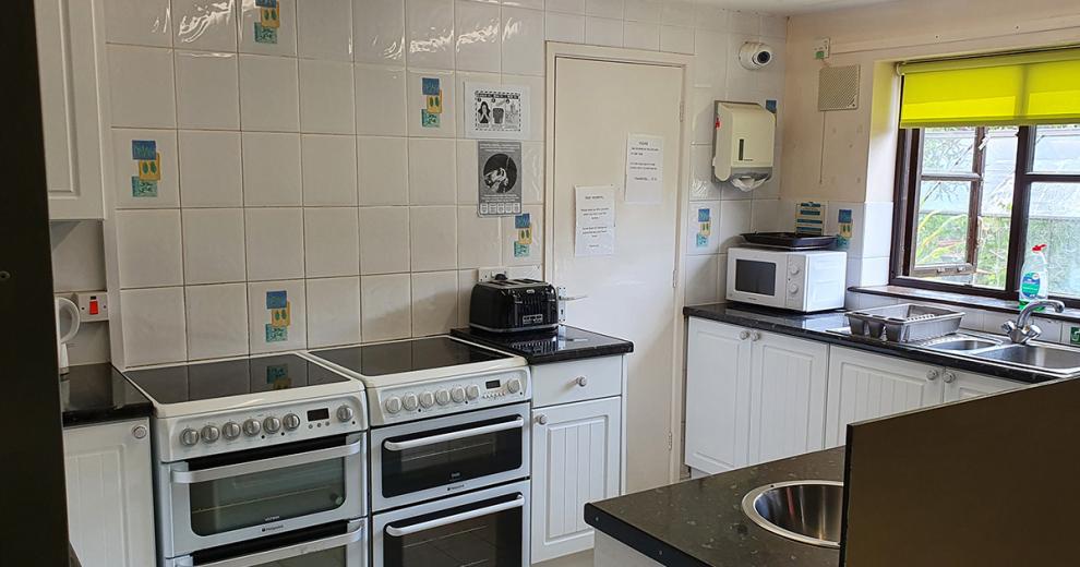 Scattered retro patterned tiled kitchen, hosting two electric ovens and hobs, modern appliances, and stainless-steel features.