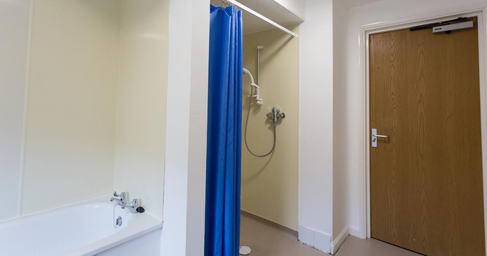 Disability accessible wet room with adjustable shower and blue privacy curtain. As well a bathroom suite.