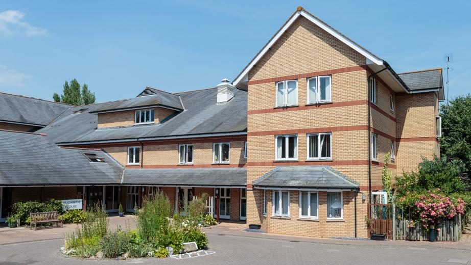 A contemporary red and yellow brick built retirement community property, set across a multi elevation floorplan, set in a well maintained driveway with circular plant feature.
