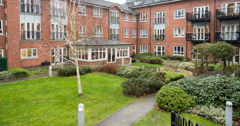 A simplistic garden area located in the middle of the property with plenty of no step access to the building. A large, grassed lawn, broken up by concrete pathways lined with lighting for clear visibility. A quiet benched seating area amongst the mature vegetation.