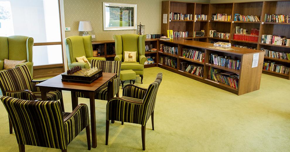 The bold green arm chairs with matching footstools look cosy and inviting in front of the multiple shelving pieces all holding an array of books. The room also hosts four lovely green, grey and black stripped chairs that surround a risen chess board on a squared table.