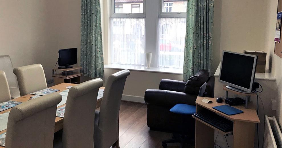Multifunctional room, with modern dining room table set, corner desk unit set up for a computer and individual seat for a television.