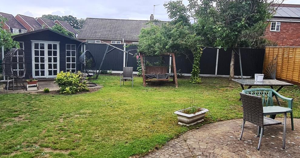 Enclosed fenced garden with outside navy and white wooden garden room, plenty of seating either on the grass or curved patio.