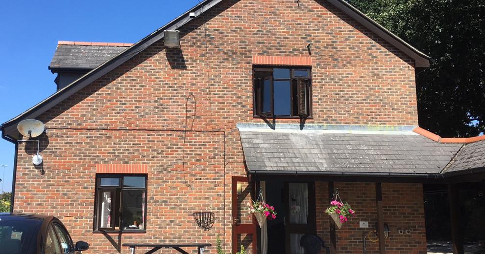 Dormer style flats with protruding top level elevation from the roof. Homely, vibrant cone hanging baskets frame the double door entryway.