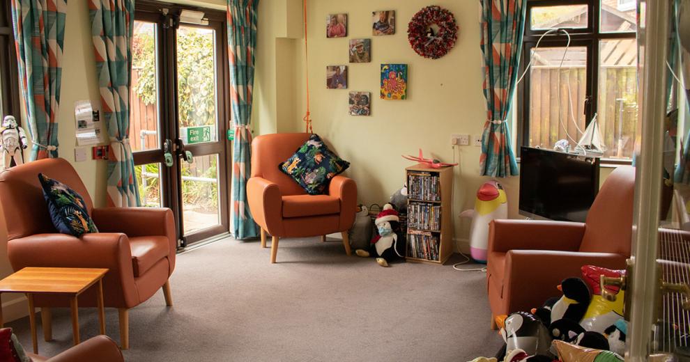 Snug, green living area with scattered brown leather individual seating and secure access out into the garden.