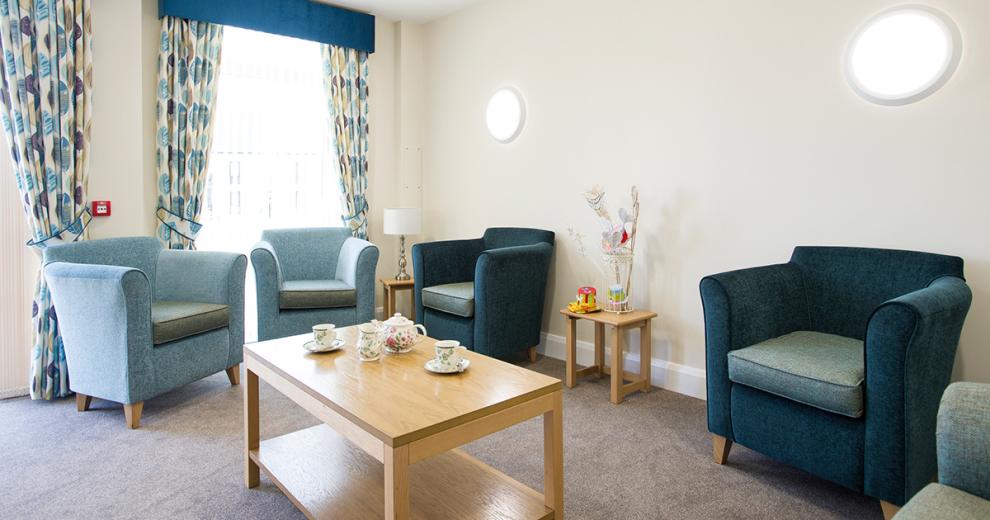 Sophisticated, mature seating area made up of numerous deluxe navy and light blue armchairs. Finished with a sizable tasteful coffee table and a collection of nesting tables being home to homely finishes.
