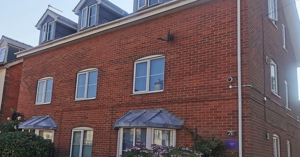 Large new build property, with three loft extensions styled in grey cladding sat above the traditional red bricked building.