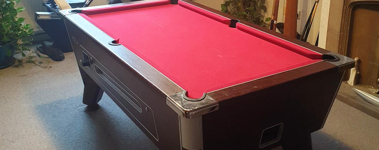 Grand oak pool table with silver accessories and red fabric table situated in a generous sized neutral room.