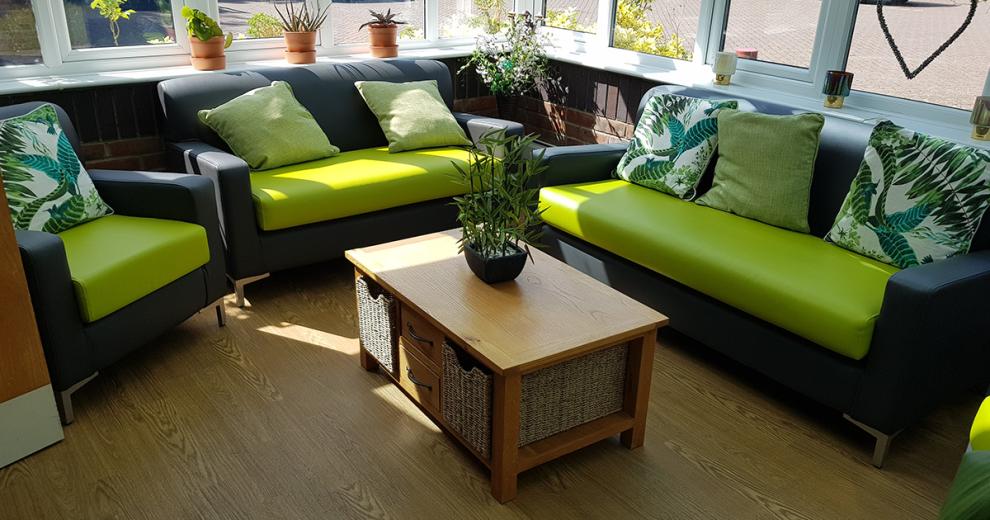 The well-lit seating area follows an outdoor colour scheme incorporating that into the lime green and charcoal grey seating, with animal print and green tone cushions. The use of natural materials such as the mixture of wicker baskets and wooden coffee table and the potted plants, seamlessly blending the outdoors and indoors.