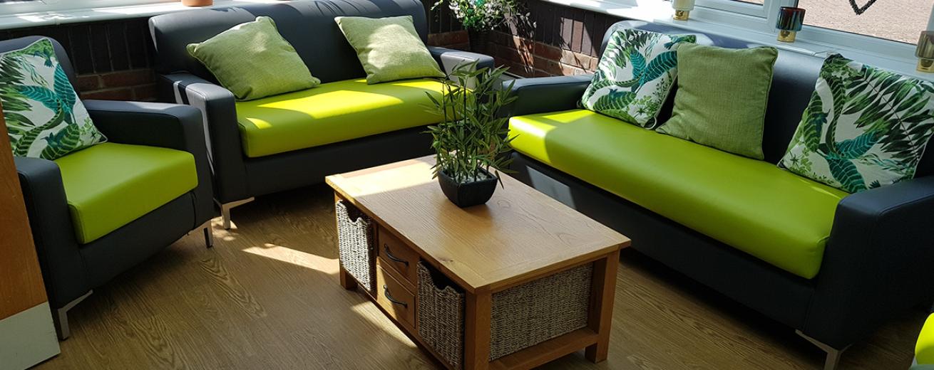 The well-lit seating area follows an outdoor colour scheme incorporating that into the lime green and charcoal grey seating, with animal print and green tone cushions. The use of natural materials such as the mixture of wicker baskets and wooden coffee table and the potted plants, seamlessly blending the outdoors and indoors.