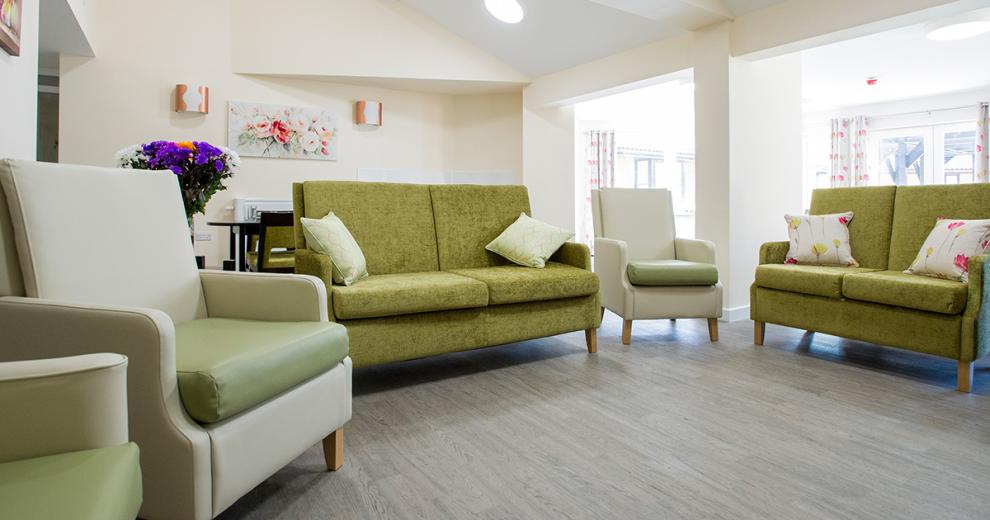 Luxurious living area using the light form the french doors to bounce off the white décor creating a stylish seating area. The arched seating compromises of two green fabric sofas and three cream and green leather armchairs.