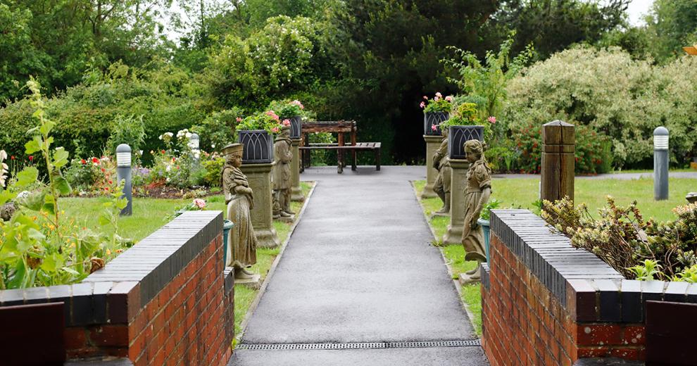 The walkways are lined with beautiful ceramic statues and planters. At the end of the walkway a bench with views of the garden is placed, before leading into a wooded area or breaking off towards the flourishing gardens.